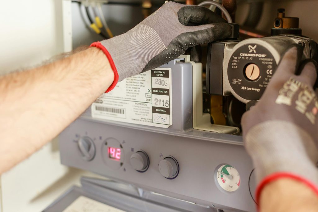 Close-up of hands adjusting a boiler system with precise instrumentation, showing maintenance work. Gros plan sur les mains ajustant un système de chaudière avec une instrumentation précise, montrant un travail de maintenance.