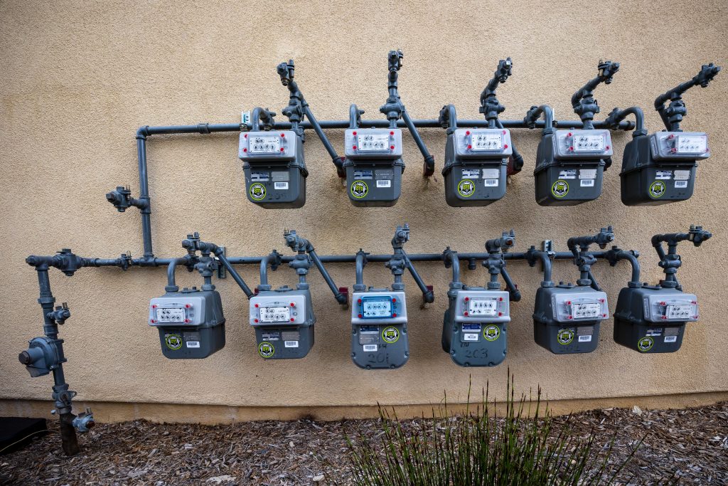 A neat installation of gas meters mounted on an exterior wall in an urban setting. Une installation soignée de compteurs de gaz montés sur un mur extérieur en milieu urbain.