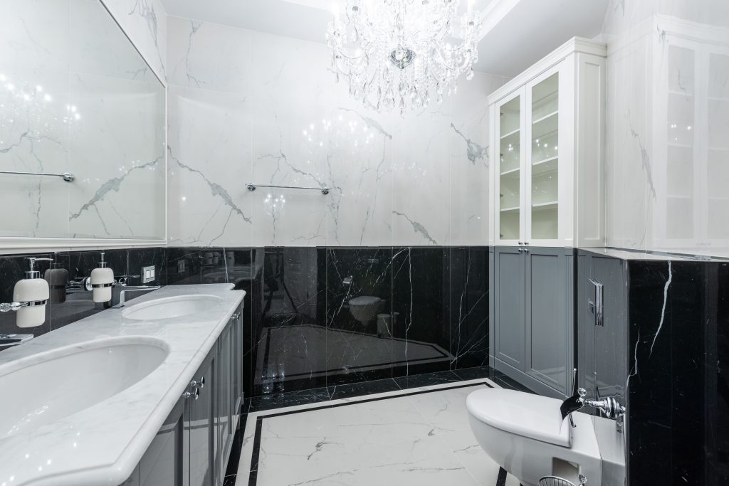 Interior of convenient modern bathroom with white clean sinks and toilet under glowing chandelier Intérieur d'une salle de bain moderne et pratique avec des lavabos blancs propres et des toilettes sous un lustre lumineux