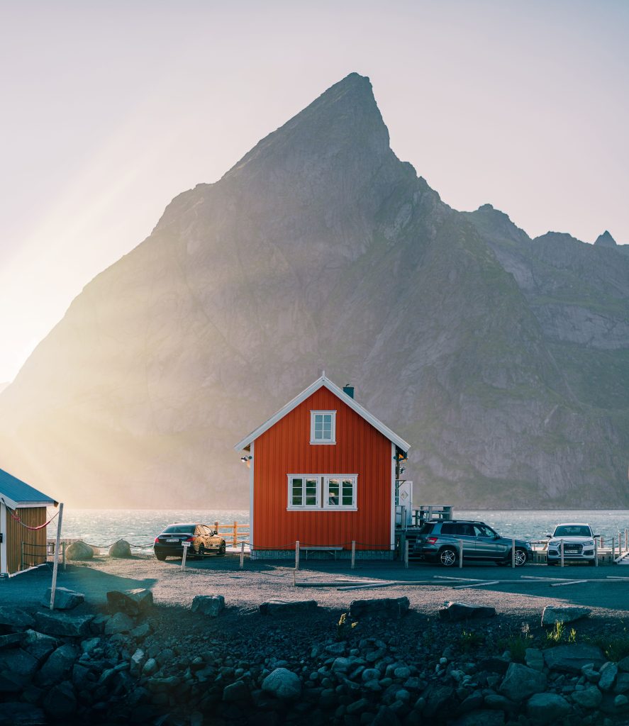 Picturesque scene of a small red house at sunset in scenic Reine, Norway. Scène pittoresque d'une petite maison rouge au coucher du soleil dans le paysage scenic de Reine, en Norvège.