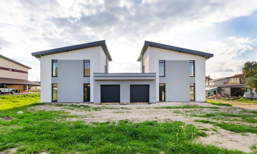 Deux maisons modernes jumelles symétriques sous ciel nuageux