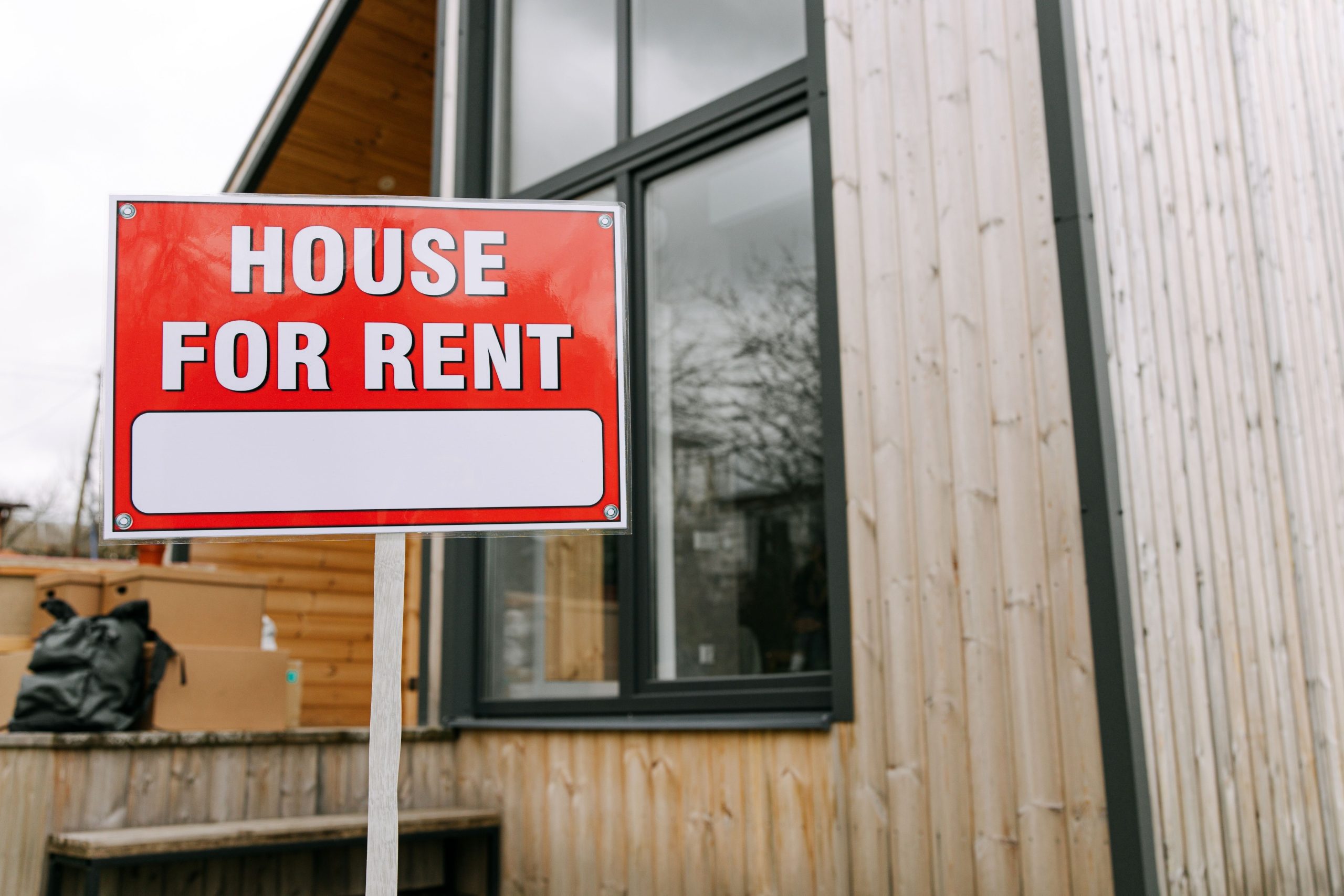 Panneau location immobilière devant maison moderne