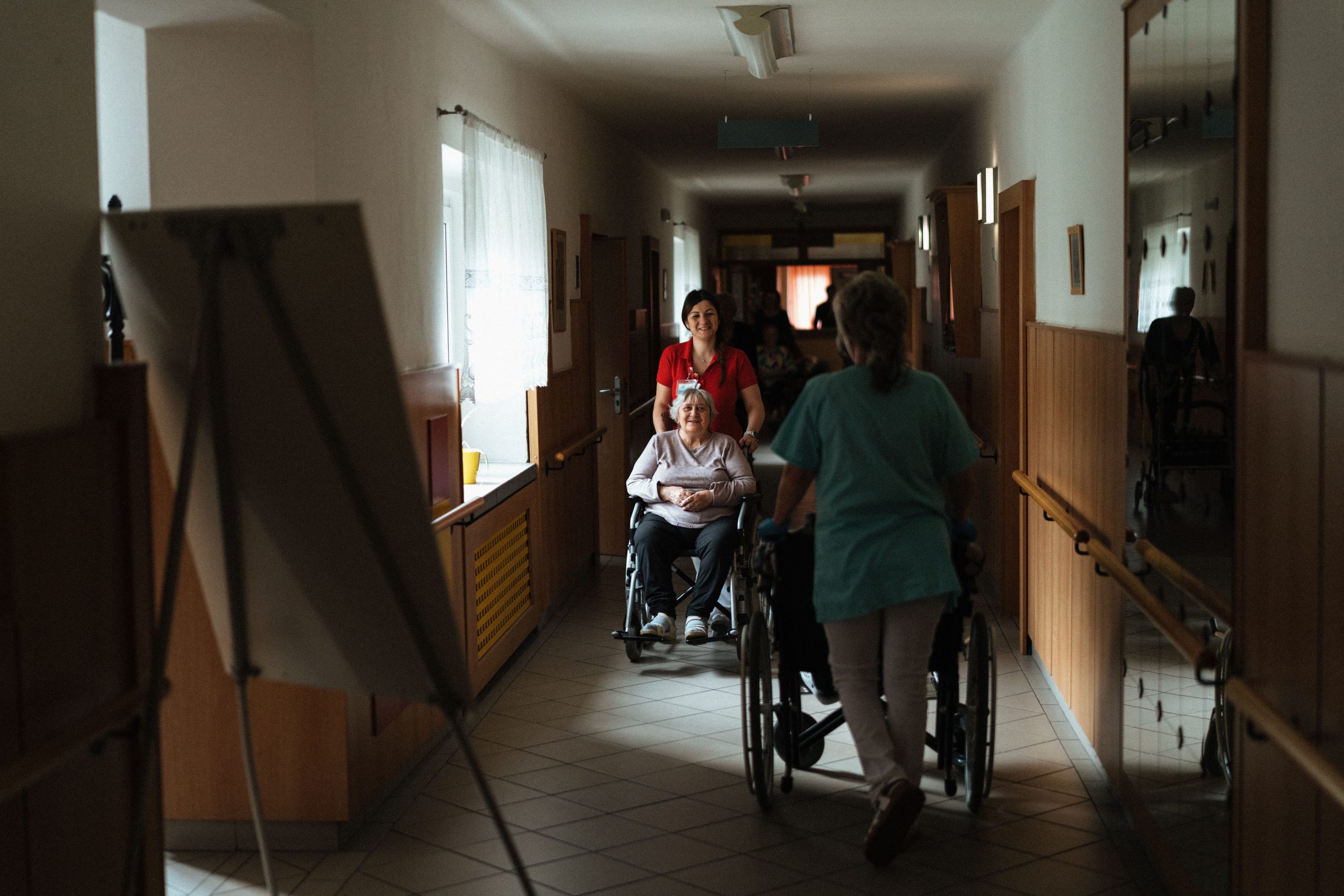 Soignante accompagnant femme âgée fauteuil couloir