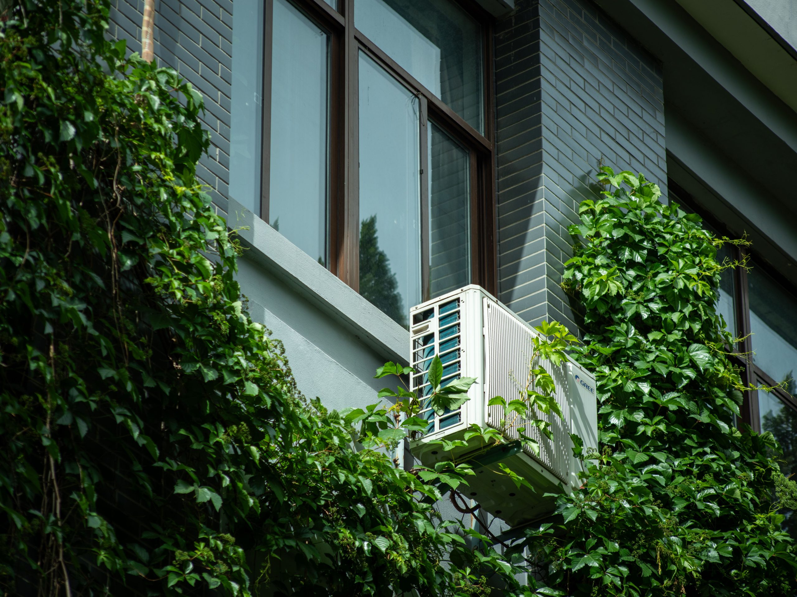 Climatiseur sur façade végétalisée du bâtiment