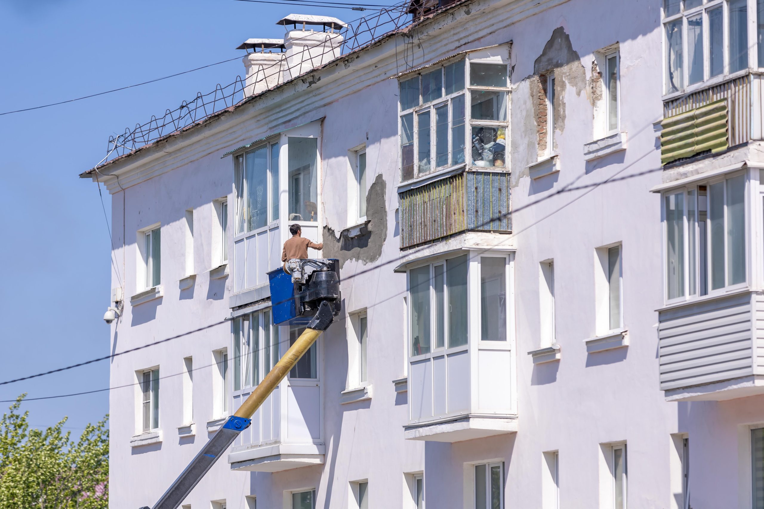 Ouvrier rénove façade avec nacelle élévatrice