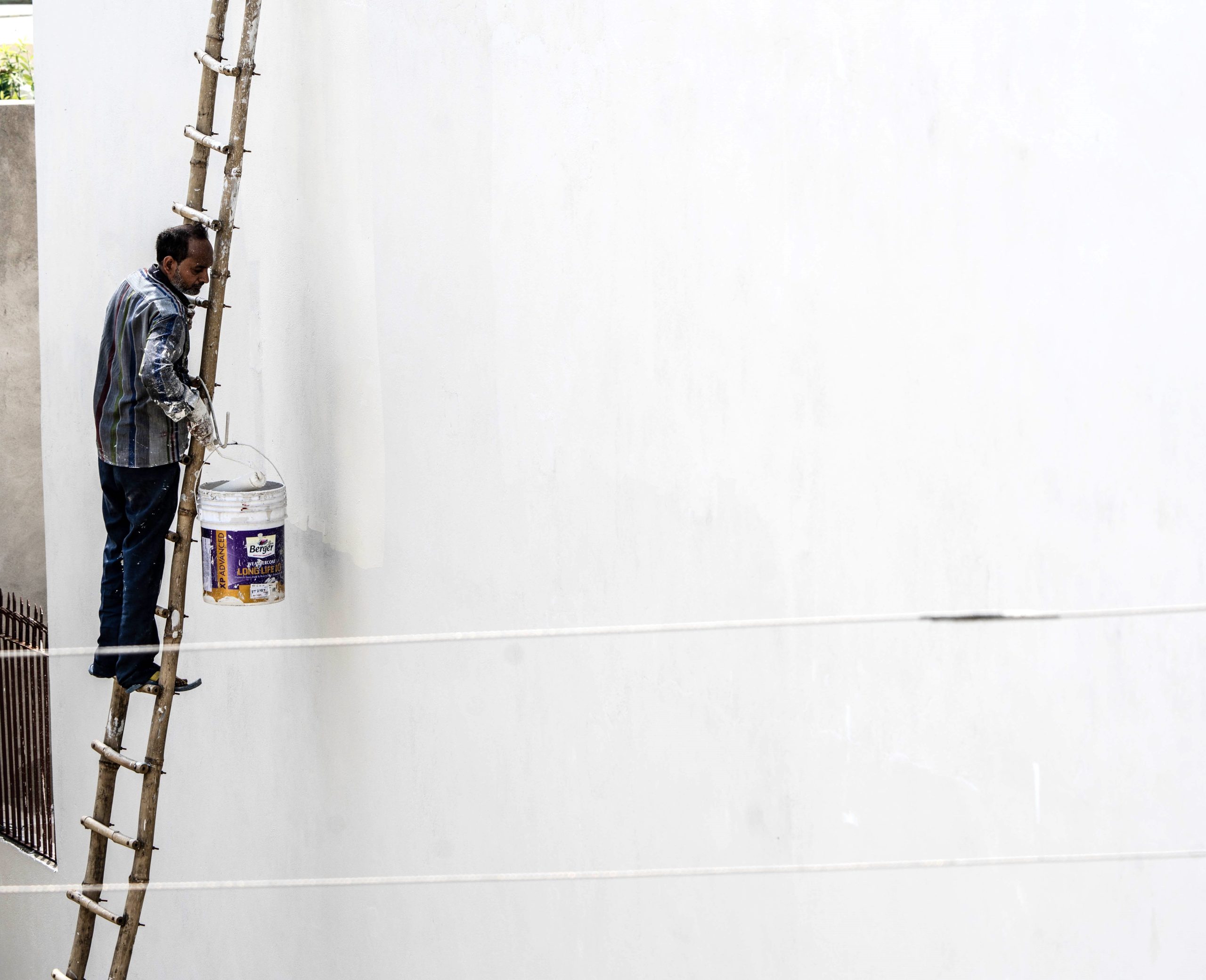 Ouvrier peint un mur blanc en extérieur