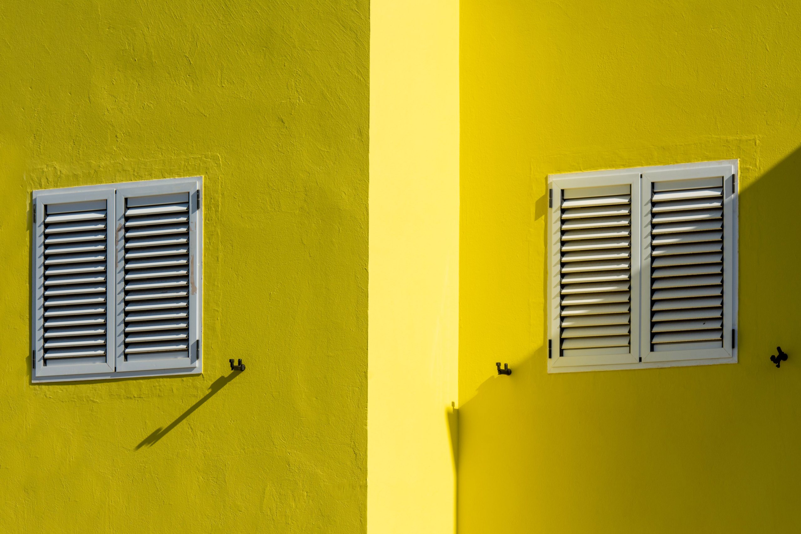 Façade jaune vif avec volets blancs
